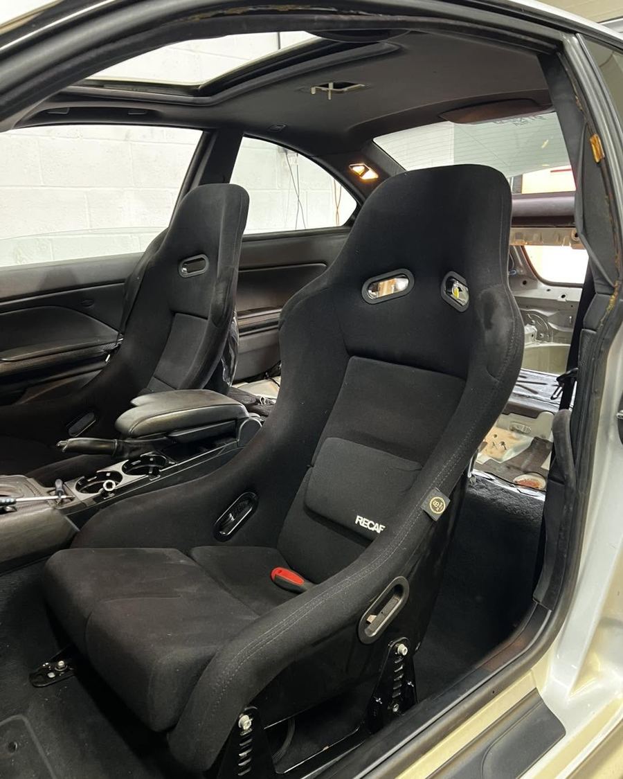 Black bucket seat fitted in a stripped interior