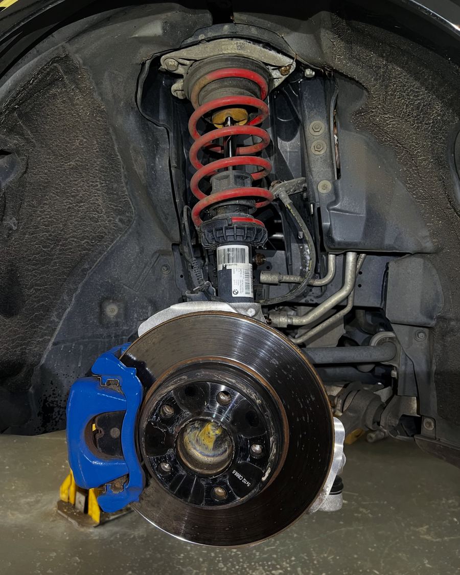 Coilover with red spring fitted above a blue big brake caliper