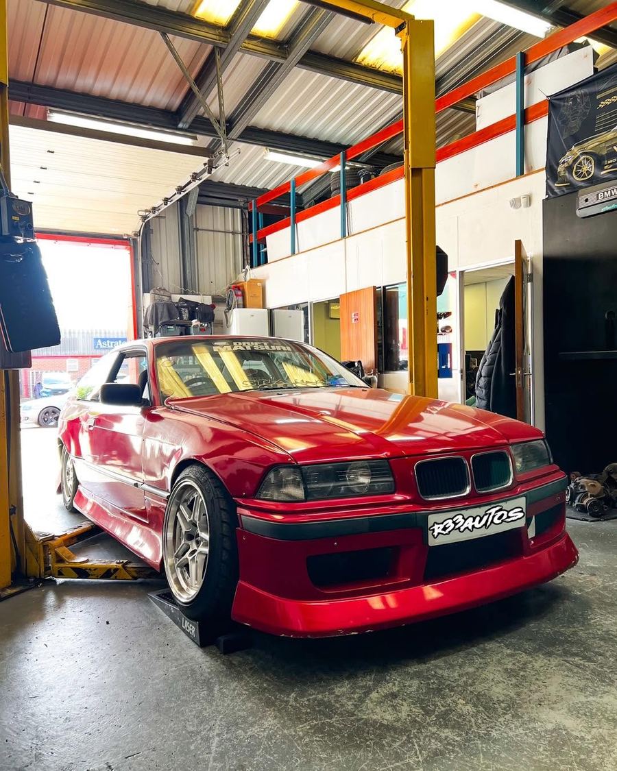Red BMW E36 on the ramp in the workshop
