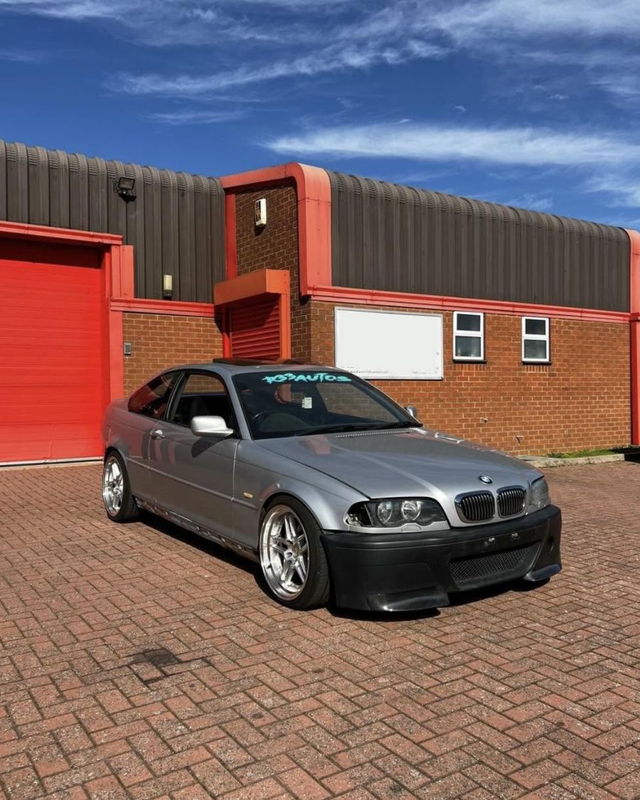 Silver BMW E46 coupe on deep-dish wheels outside the unit