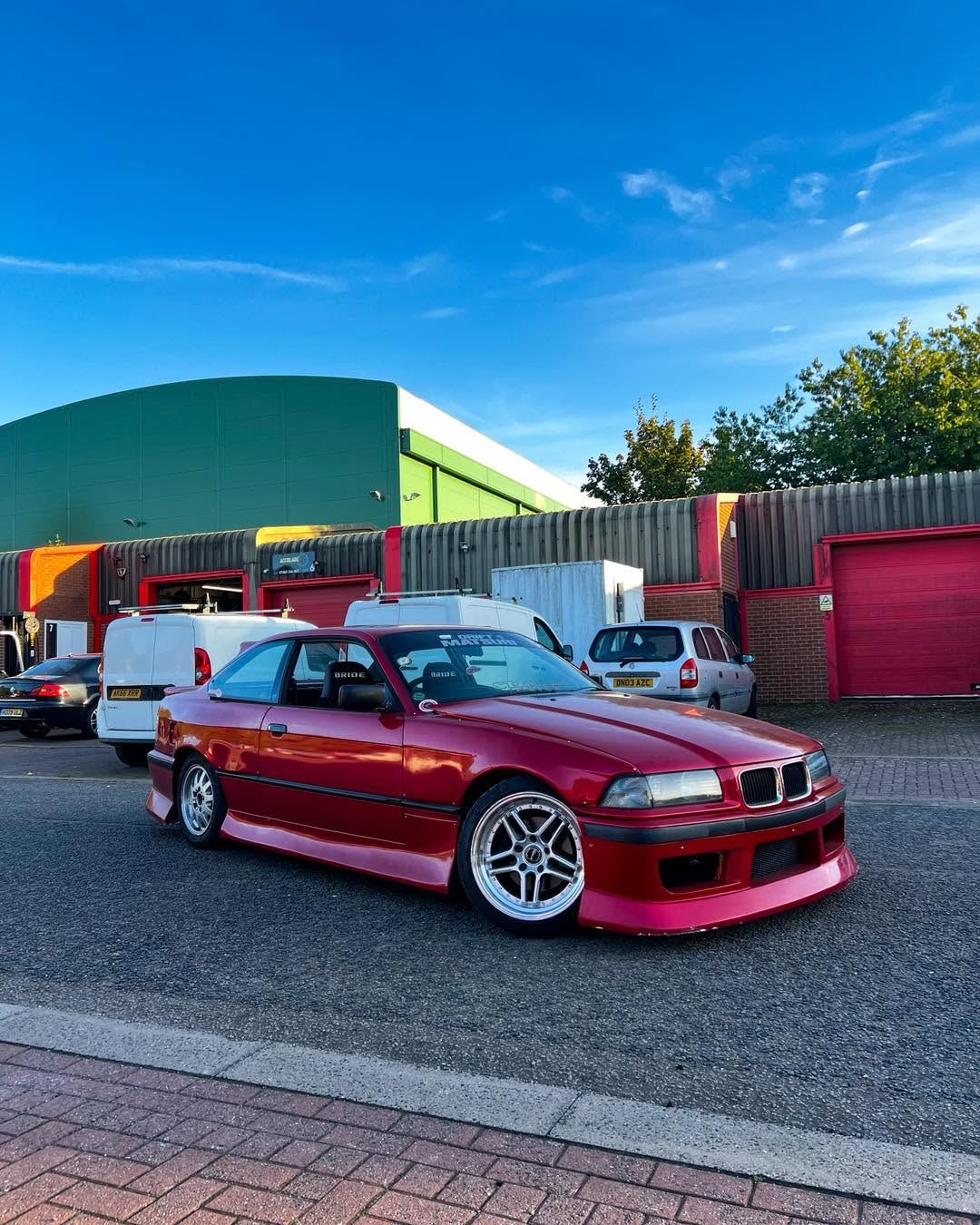 Red BMW E36 coupe on wide silver wheels outside the R33 Autos unit